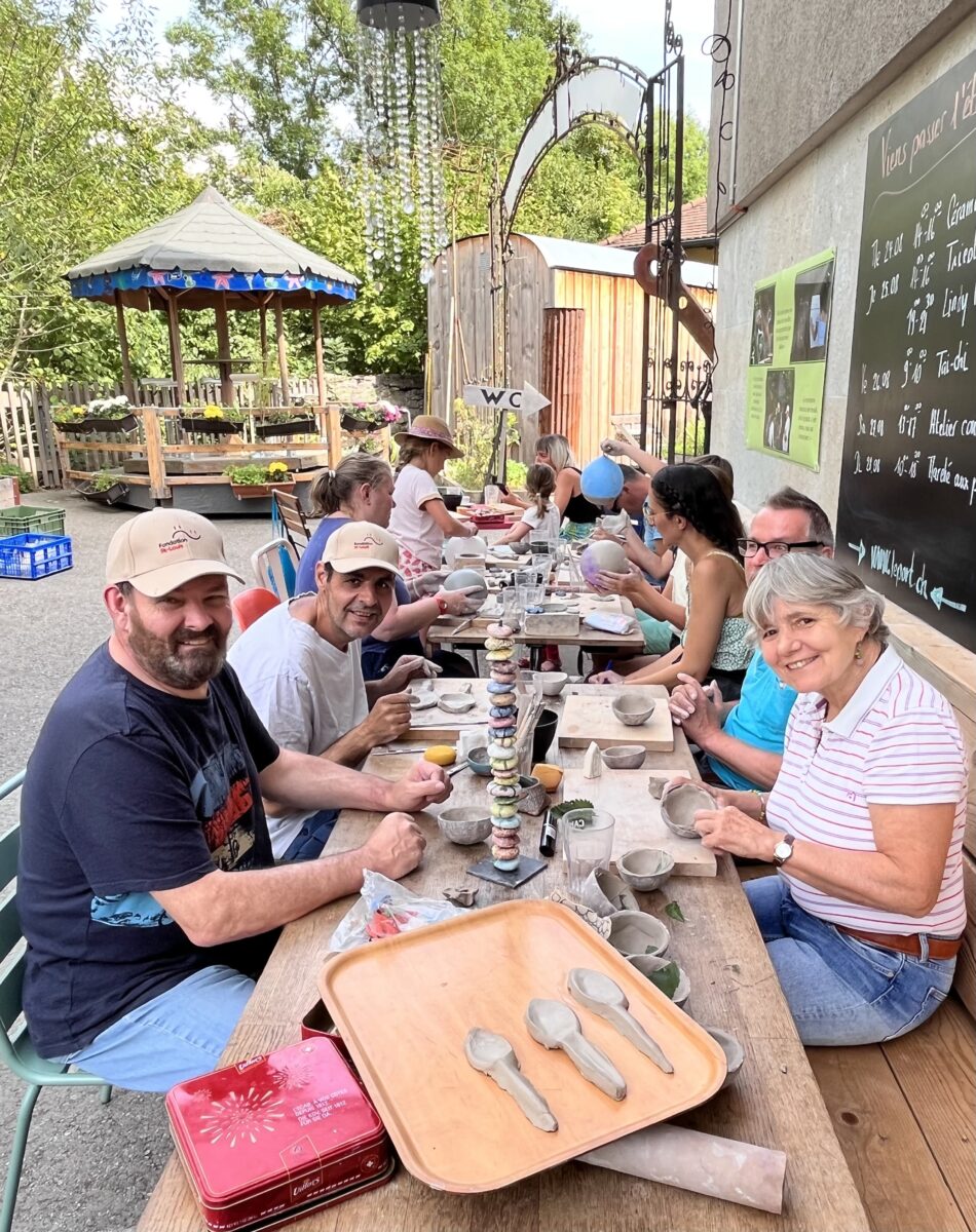 une dizaine de personnes autour d'une table qui font de la céramique