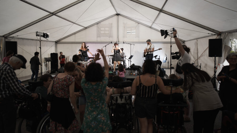 Un concert sous une tente. Dans le public, plusieurs personnes son en fauteuil roulant